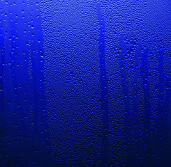 Macro shot of liquid condensate on glass, abstract blue background