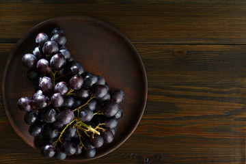 Dark purple grape on wooden plate. Vintage wooden table, high resolution