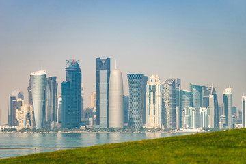 Fototapeta na wymiar Panoramic view of modern skyline of Doha with green grass foreground. Concept of healthy environment