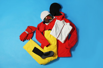 Stylish winter sport clothes on light blue background, flat lay
