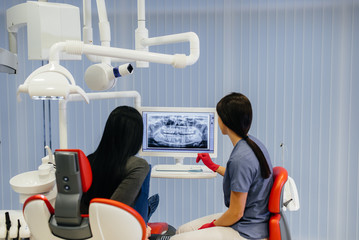 The dentist shows a picture of the patient's teeth and tells the necessary treatment. Dentistry,...