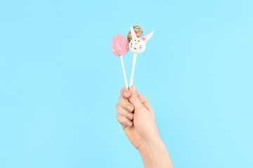 Woman with delicious cake pops on light blue background, closeup. Easter holiday
