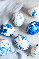 Dyed Easter eggs. Сlassic blue Easter eggs on the grey background. Blue speckled easter eggs with paint and brushes. Decorating eggs, preparing for Easter