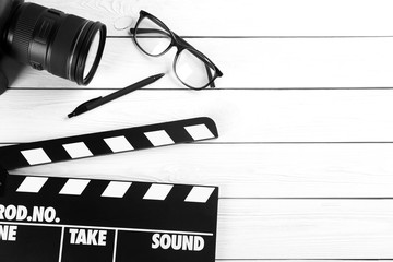 Flat lay composition with camera and movie clapper on white wooden table, space for text. Video...