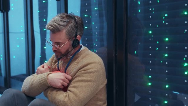 Lonely depressed data center worker sitting in frustration on floor in server cabinet room regret about what happened. Sad Valentine. People in IT tech environment.