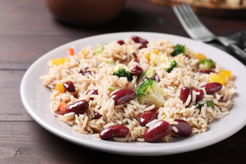 Delicious rice with beans served on wooden table, closeup