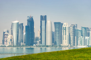 Fototapeta premium Panoramic view of modern skyline of Doha with green grass foreground. Concept of healthy environment