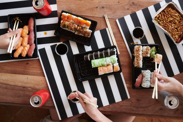 Crop women eating sushi together