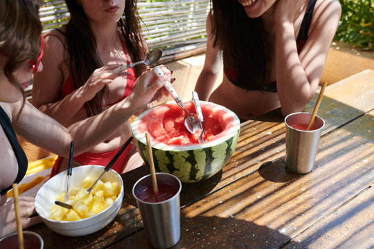 Crop women eating watermelon on terrace