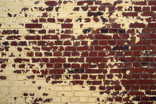 Gros plan sur un mur de briques rouges avec de la peinture de couleur beige et noire.