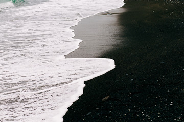 a sea wave arrives on the shore with black volcanic sand . beautiful natural background in Iceland