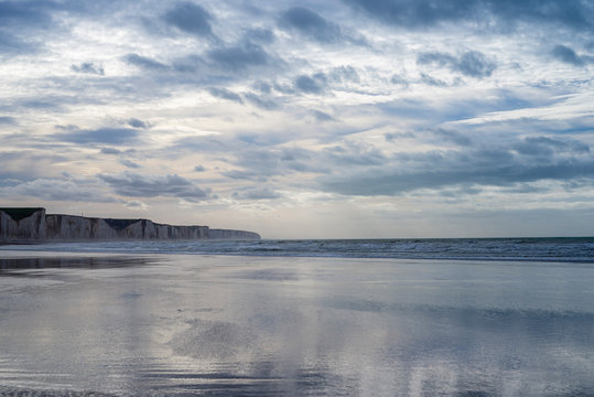 Falaises de Caux. Somme. la plage de sable est &agrave; mar&eacute;e basse. Des nappes d'eau se sont form&eacute;es sur la plage. Le ciel nuageux se reflete dans ces flaques d'eau. Les falaises en craie s'&eacute;tendent jusqu'&agrave;