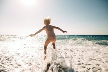 Rear view of girl jumping in sea