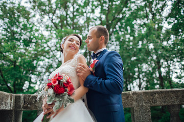 The bride in a beautiful dress the groom stylishly dressed. Bride and groom in garden on their wedding, photo session. Sincere emotions. Beautiful wedding bouquet