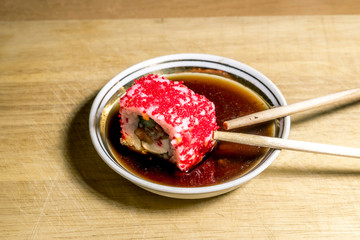 Sushi in soy sauce and sticks on the table