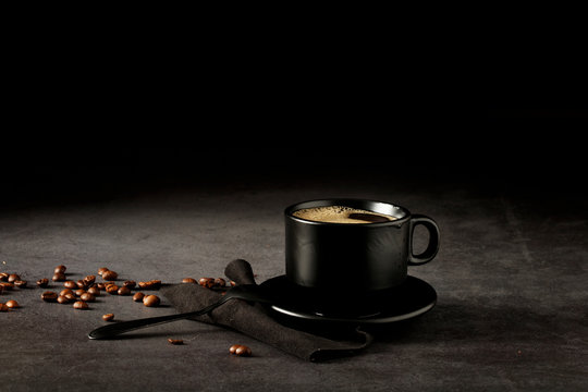 Black coffee cup with coffee on a dark background. With copy space for your text. Cup of coffee on a black background low key copy space.