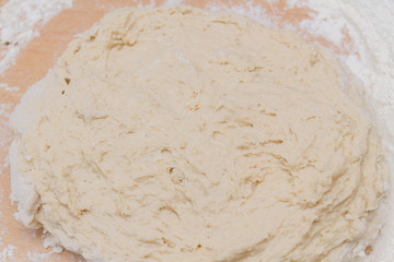 Kneading dough with flour on a wooden table at home