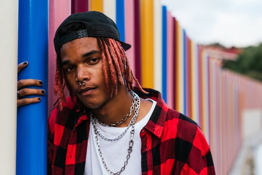 Portrait of a brown skinned young man with dreadlocks looking serious at the camara