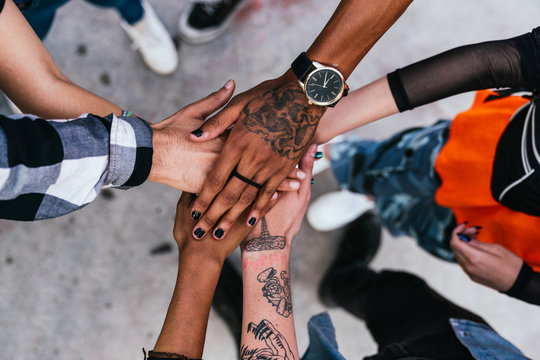 friends putting their hands together in park.