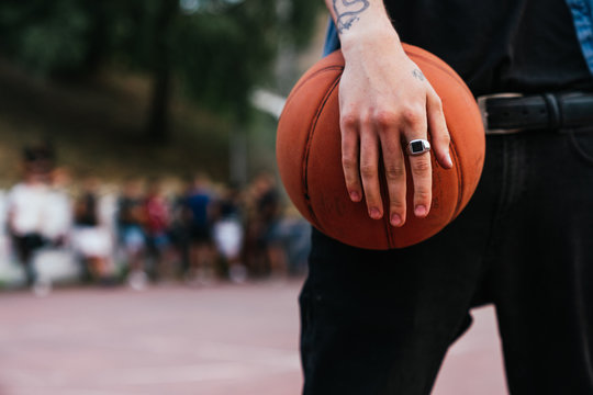 close up of a hand with a ring holding a basket ball