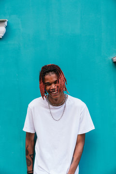 Portrait of a cheerful young man with dreadlocks, wearing a white t shirt.
