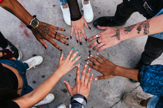 group of friends put their hands together in a circle. Diversity