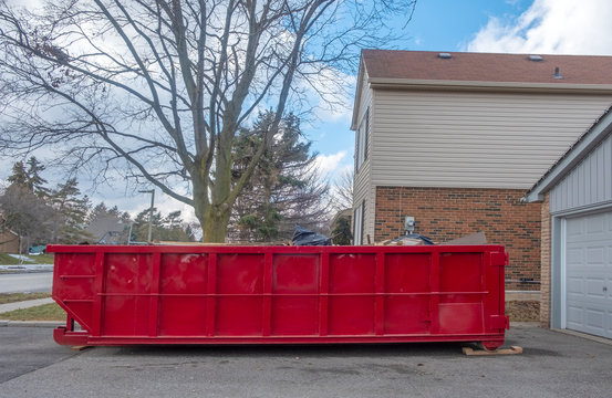 Red Dumpster Bin on the Driveway of a Suburban House