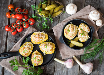 Stuffed potatoes with champignons, bacon, tomatoes and cheese. The concept of proper nutrition. Two cast-iron pans on a wooden background.