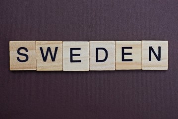  gray word sweden from small wooden letters on a brown table