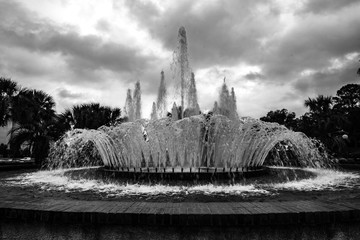 circular water fountain with cloudy skies in black and white