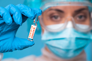 A female doctor, an employee of a scientific laboratory, holds in her hand a medical ampoule with a vaccine against coronavirus. COVID-19. 2019 Novel Coronavirus (2019-nCoV).