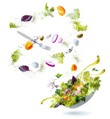 Flying ingredients salad isolated on a white background. A white plate with salad and floating in...