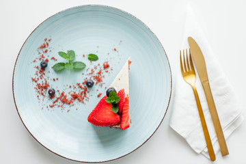 A beautiful piece of cake with berries with butter cream on a white background. Cake with red cakes.