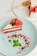 A beautiful piece of cake with berries with butter cream on a white background. Cake with red cakes.