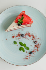 A beautiful piece of cake with berries with butter cream on a white background. Cake with red cakes.