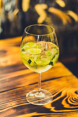 Prickelnder Cocktail im Glas mit Limetten und Eis auf Tisch in Bar