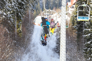 Couple using chairlift at mountain ski resort. Winter vacation