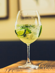 Prickelnder Cocktail im Glas mit Limetten und Eis auf Tisch in Bar