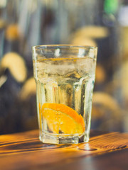 Prickelnder Cocktail im Glas mit Orangescheiben und Eis auf Tisch in Bar
