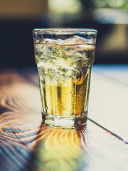 Prickelnder Cocktail im Glas mit Eis auf Tisch aus Holz in Bar