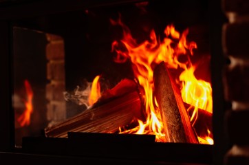 Obraz premium Fireplace with burning wood, closeup view. Winter vacation