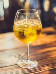 Prickelnder Cocktail im Glas mit Limetten und Eis auf Tisch aus Holz in Bar