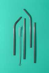 Metal reusable cocktail tubes, minimalistic zero waste concept and eco friendly, emerald background