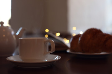 Delicious morning coffee and croissant served for breakfast on wooden table