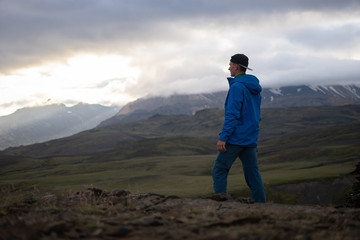 Fototapeta premium Backside of tall caucasian man wearing jacket standing in over snowy mountain on the Laugavegur track, Iceland. Promoting healthy lifestyle