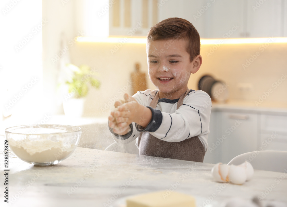 Poster Cute little boy cooking dough at table in kitchen