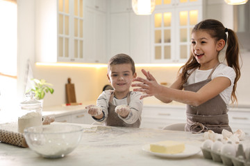 Cute little children cooking dough together in kitchen
