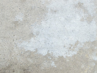 grey concrete floor with many traces of wear and tear due to foot traffic.