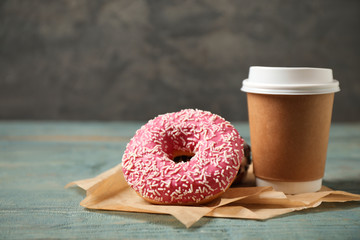Yummy donuts with sprinkles and paper cup on wooden table - obrazy, fototapety, plakaty