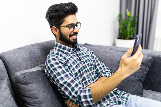 Young Indian Man Have Video Call Conversation On The Phone Lying At Couch At Home